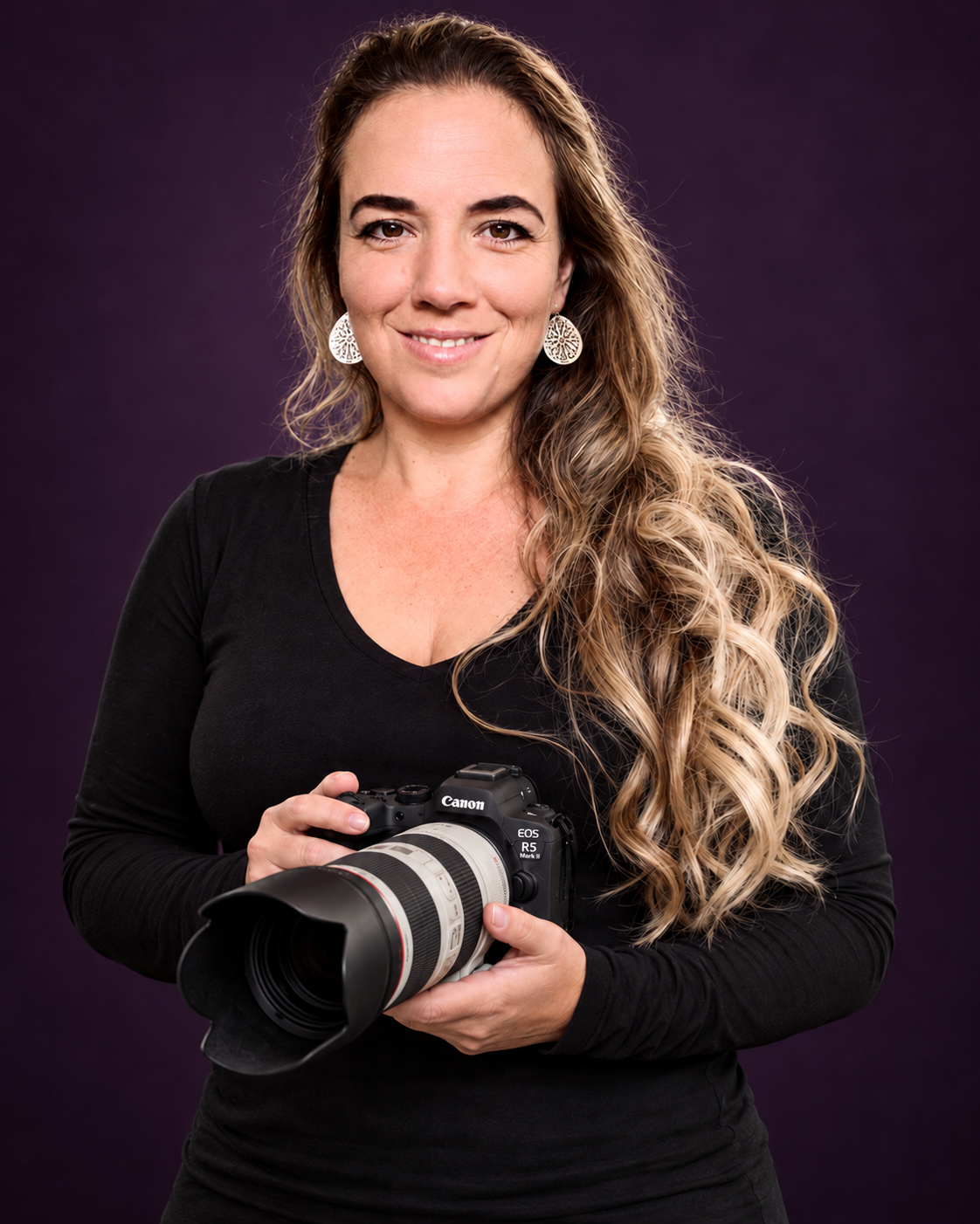 Cyrille Deuzé kijkt naar de bezoeker en houdt een Canon-camera met telelens vast, tegen een donkerpaarse achtergrond